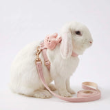 Load image into Gallery viewer, A white rabbit wearing an adjustable pink bunny harness and leash set with a cute plush charm, sitting on a clean white background.
