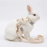 Load image into Gallery viewer, A white rabbit sitting next to a neatly coiled 78-inch leash, wearing a beige escape-resistant rabbit harness.
