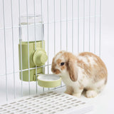 Load image into Gallery viewer, A brown and white bunny drinking fresh water from a mint green cage-mounted automatic waterer dispenser.