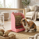 Load image into Gallery viewer, A charming lifestyle photograph of a tri-color calico lop-eared rabbit in a stylish, modern living room setting, eating hay from a pink hay feeder mounted on a clear and wood-frame playpen fence. The setup includes various woven chew toys, creating a cohesive small pet play area