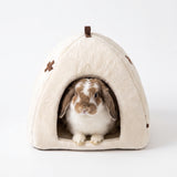 Load image into Gallery viewer, Small lop bunny sitting inside a cozy cream plush rabbit cave bed on a clean white background.