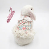 Load image into Gallery viewer, White Holland Lop bunny wearing an adjustable floral print rabbit harness dress with matching pink leash for outdoor walking.