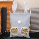 Load image into Gallery viewer, A small serene blue hanging bunny grass pellet dispenser bag with two windows filled with grass pellets, securely mounted to a modern indoor wire pet cage.